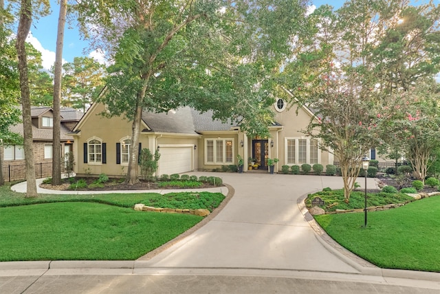 view of front of house featuring a front yard, a garage, driveway, and stucco siding