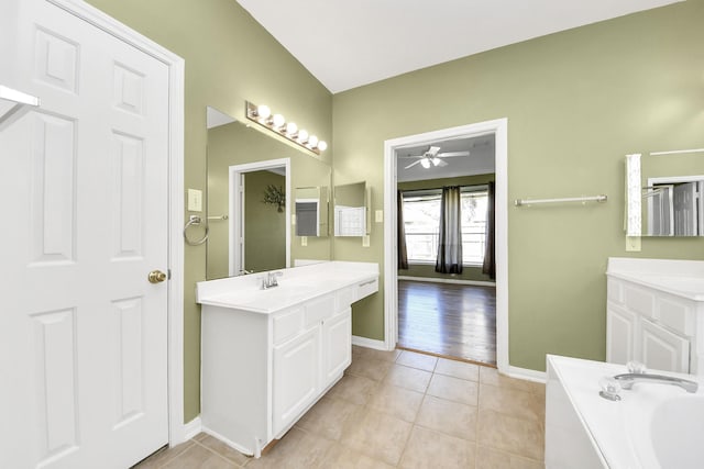 full bath with tile patterned floors, a bath, baseboards, and two vanities