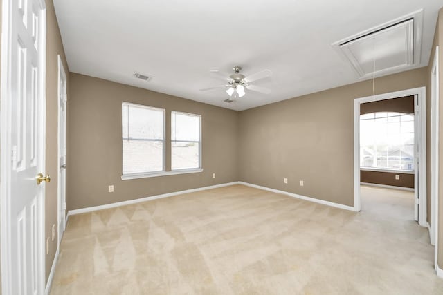 spare room with attic access, baseboards, visible vents, and light carpet