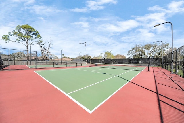 view of tennis court featuring community basketball court and fence