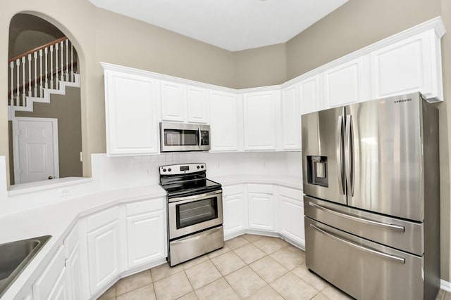 kitchen with white cabinetry, light countertops, light tile patterned floors, and stainless steel appliances