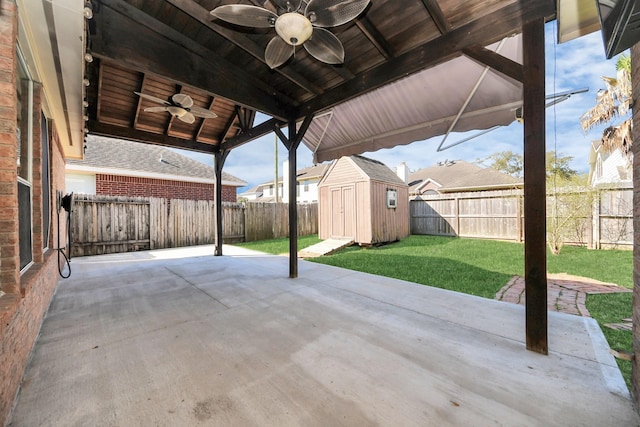 view of patio / terrace with ceiling fan, a fenced backyard, an outdoor structure, and a shed