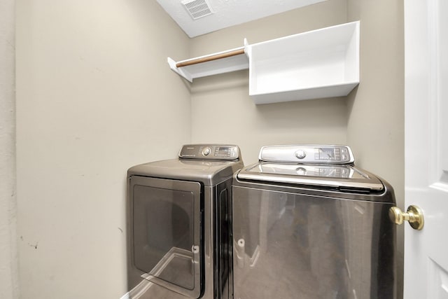 clothes washing area with independent washer and dryer, laundry area, and visible vents