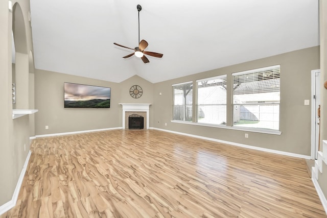 unfurnished living room featuring a ceiling fan, wood finished floors, baseboards, a fireplace, and vaulted ceiling