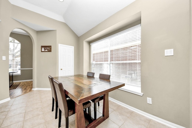 dining area with arched walkways, baseboards, a wealth of natural light, and vaulted ceiling