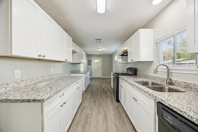 kitchen with visible vents, under cabinet range hood, light wood-style flooring, black appliances, and a sink