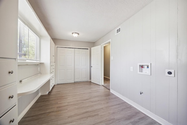 interior space with hookup for an electric dryer, hookup for a washing machine, laundry area, and light wood finished floors