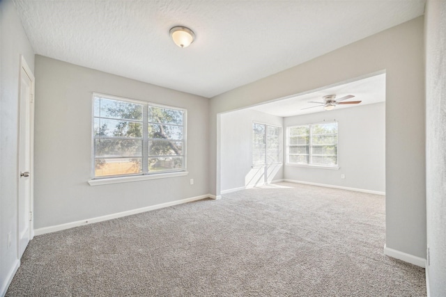 spare room featuring carpet, baseboards, and a textured ceiling