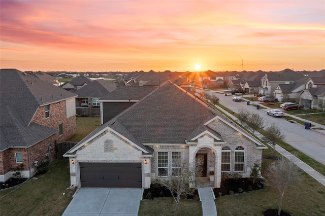 traditional home featuring a lawn, a residential view, concrete driveway, a shingled roof, and a garage