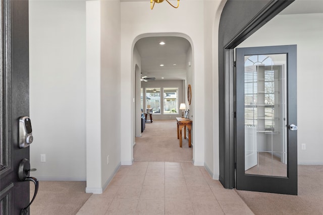 interior space with recessed lighting, baseboards, arched walkways, and light carpet