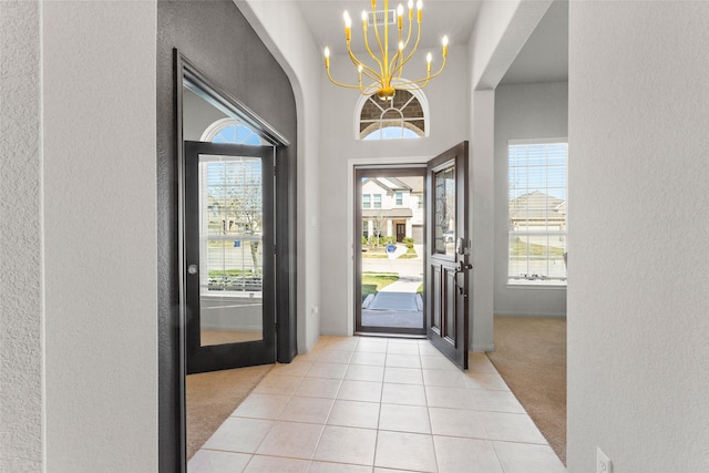 foyer entrance featuring visible vents, light tile patterned flooring, light colored carpet, and plenty of natural light