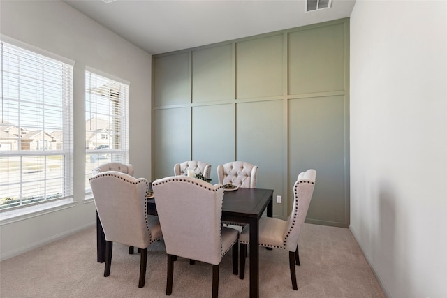 dining room with a decorative wall, baseboards, visible vents, and light carpet