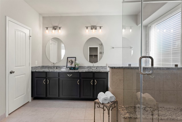 bathroom featuring a shower stall, double vanity, tile patterned floors, and a sink