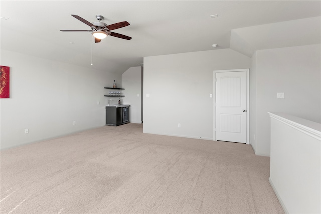 unfurnished living room with indoor wet bar, lofted ceiling, light colored carpet, and ceiling fan