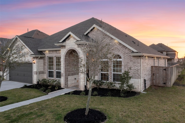 view of front of house with a front lawn, driveway, stone siding, and roof with shingles