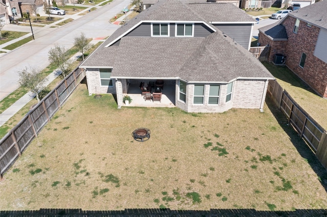 back of property featuring central air condition unit, a fire pit, roof with shingles, brick siding, and a patio area