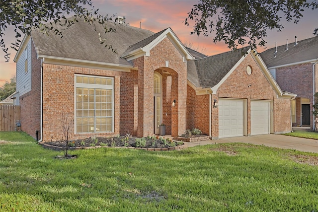 view of front of home featuring a lawn, roof with shingles, concrete driveway, an attached garage, and brick siding