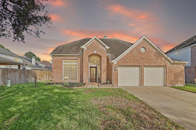 traditional home featuring brick siding, fence, concrete driveway, a lawn, and a garage