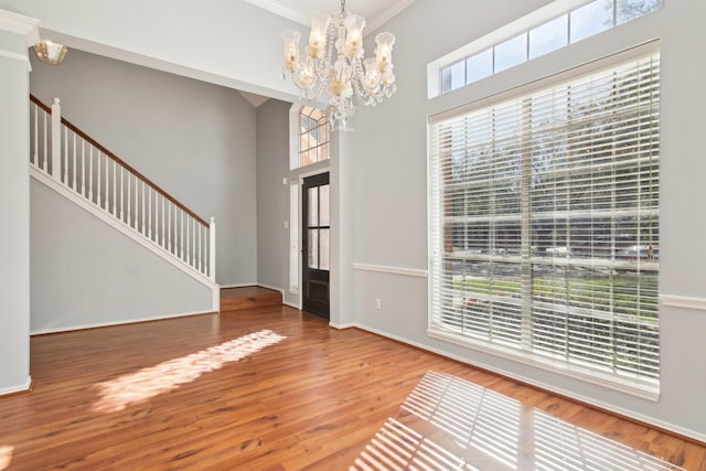 interior space with baseboards, a chandelier, stairs, a high ceiling, and wood finished floors