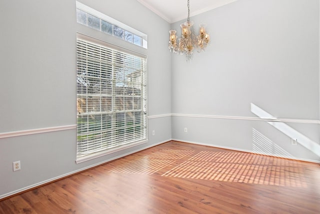 unfurnished dining area with crown molding, a notable chandelier, and wood finished floors