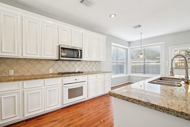 kitchen featuring tasteful backsplash, visible vents, appliances with stainless steel finishes, white cabinets, and a sink