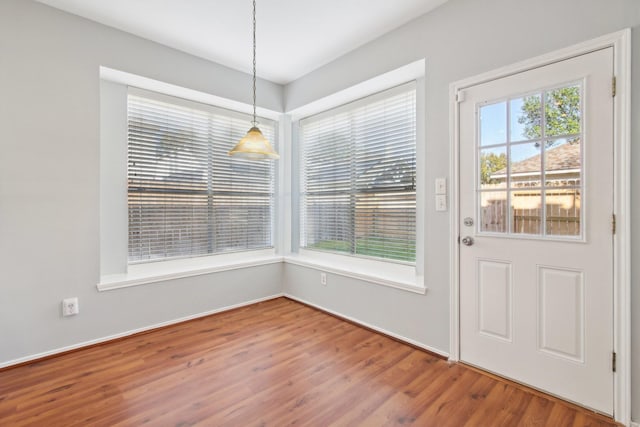 unfurnished dining area featuring wood finished floors and baseboards