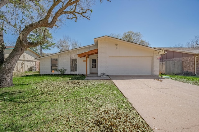 mid-century modern home with a front yard, brick siding, an attached garage, and driveway