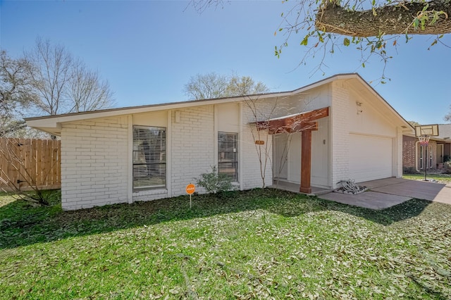 view of front facade with a front yard, fence, driveway, an attached garage, and brick siding