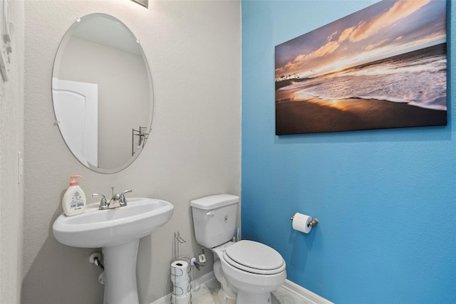 bathroom featuring a sink, baseboards, and toilet