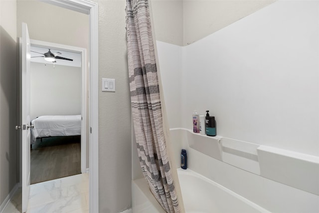 ensuite bathroom featuring shower / bath combo with shower curtain, a ceiling fan, marble finish floor, and connected bathroom