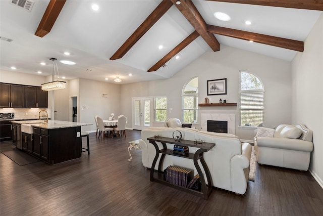 living area with visible vents, beamed ceiling, dark wood finished floors, a high end fireplace, and baseboards