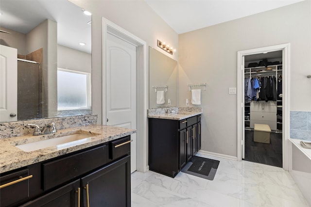 full bath with a walk in closet, two vanities, marble finish floor, a sink, and a shower stall