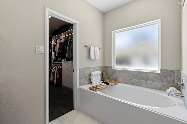 full bathroom with a garden tub and a spacious closet