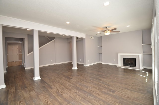 finished basement featuring a fireplace with raised hearth, ceiling fan, baseboards, recessed lighting, and wood finished floors