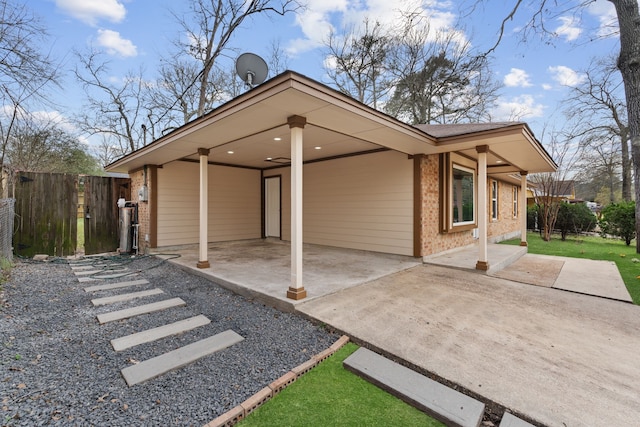 exterior space with a patio, brick siding, a carport, and fence