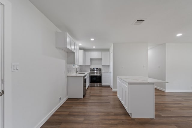 kitchen featuring visible vents, a kitchen island, a sink, appliances with stainless steel finishes, and backsplash