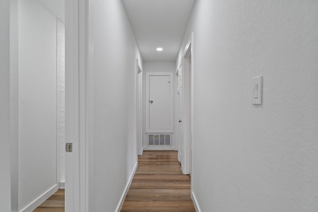 corridor with visible vents, dark wood-style flooring, and baseboards