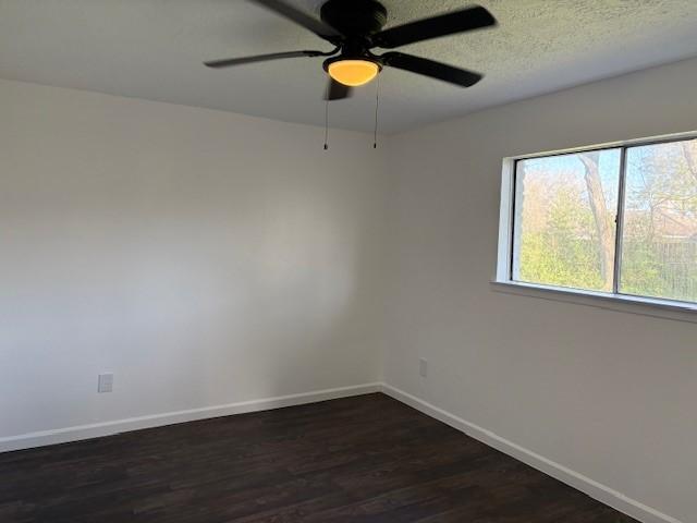 unfurnished room featuring a textured ceiling, a ceiling fan, baseboards, and dark wood-style flooring