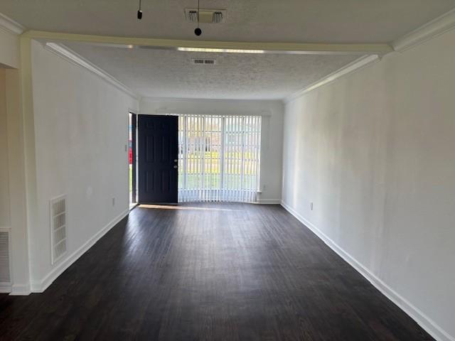 unfurnished room featuring dark wood finished floors, visible vents, and ornamental molding