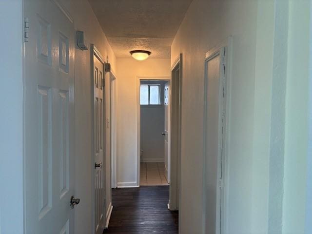 hallway featuring a textured ceiling and dark wood finished floors