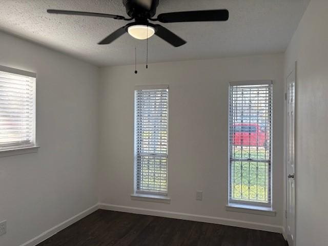 unfurnished room featuring plenty of natural light, a textured ceiling, and dark wood-type flooring