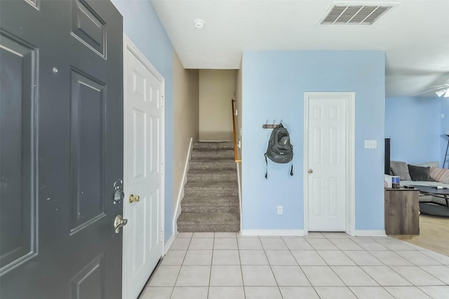 foyer entrance featuring visible vents, baseboards, light tile patterned flooring, and stairway