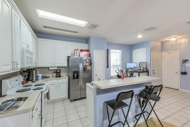 kitchen with white cabinets, white appliances, a breakfast bar area, and light countertops