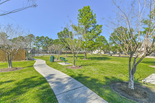 view of community featuring a lawn and fence