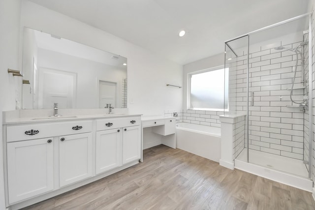 full bathroom featuring a shower stall, a garden tub, wood finished floors, and a sink