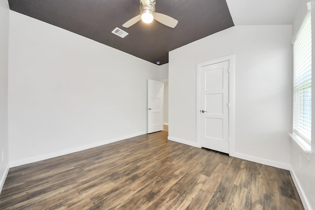 unfurnished bedroom featuring visible vents, baseboards, dark wood finished floors, and vaulted ceiling