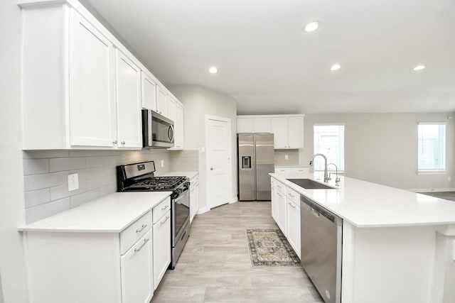 kitchen with light wood finished floors, white cabinets, stainless steel appliances, and a sink