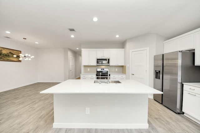 kitchen featuring a kitchen island with sink, visible vents, light countertops, stainless steel appliances, and a sink