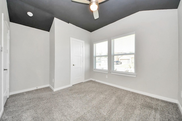 empty room featuring baseboards, carpet floors, ceiling fan, and vaulted ceiling