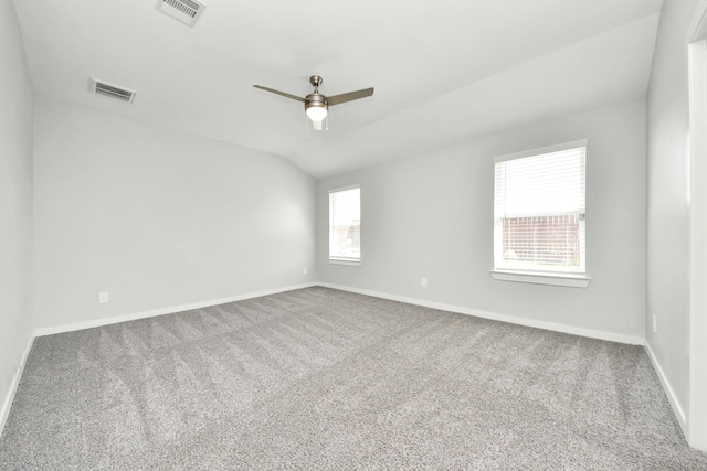 empty room featuring vaulted ceiling, carpet flooring, visible vents, and ceiling fan